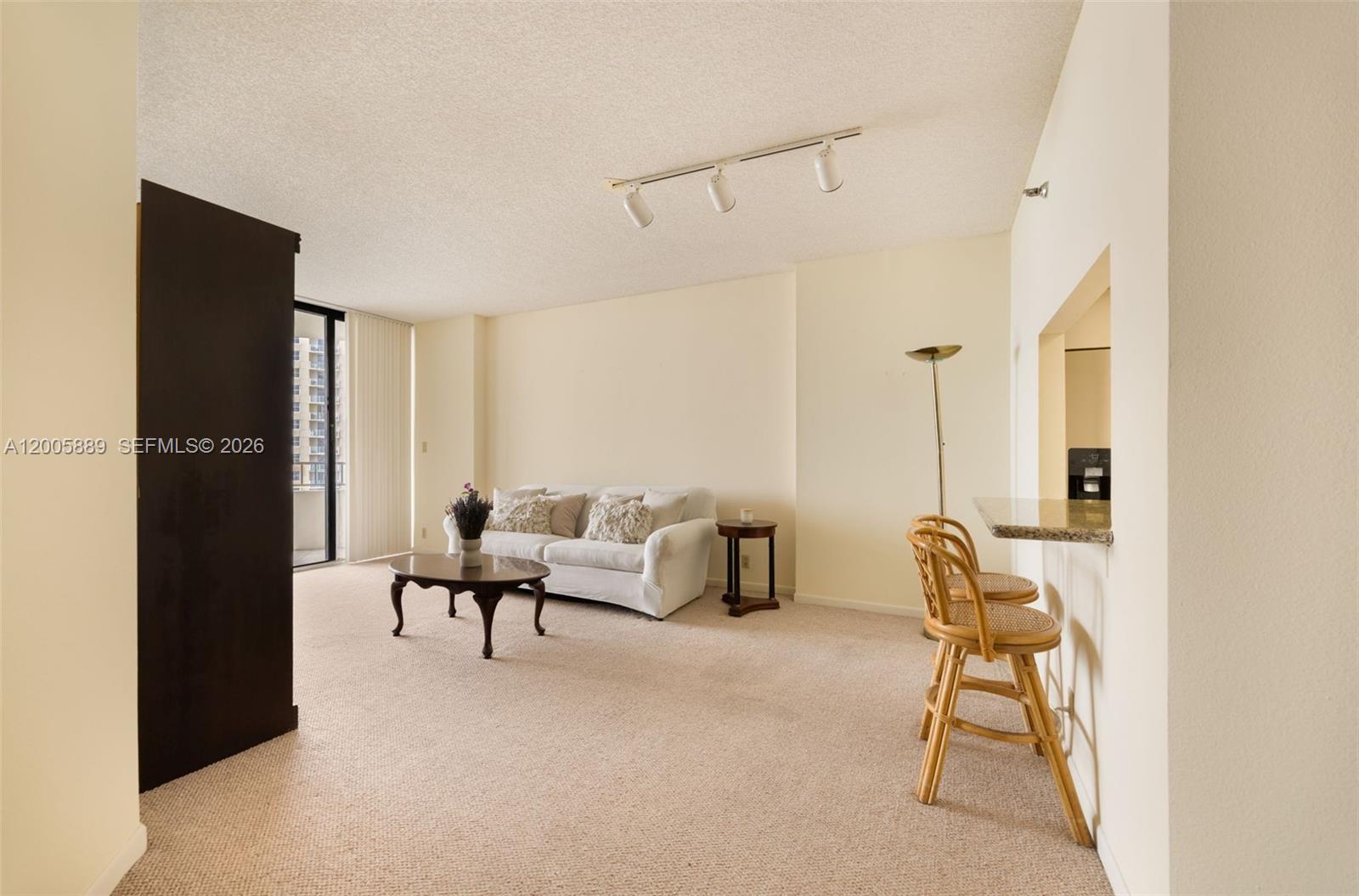 A living room features beige carpeting, a white sofa, a coffee table, and a breakfast bar — 520 Brickell Key Dr # A1001, Miami FL 33131, MIAMI, FL