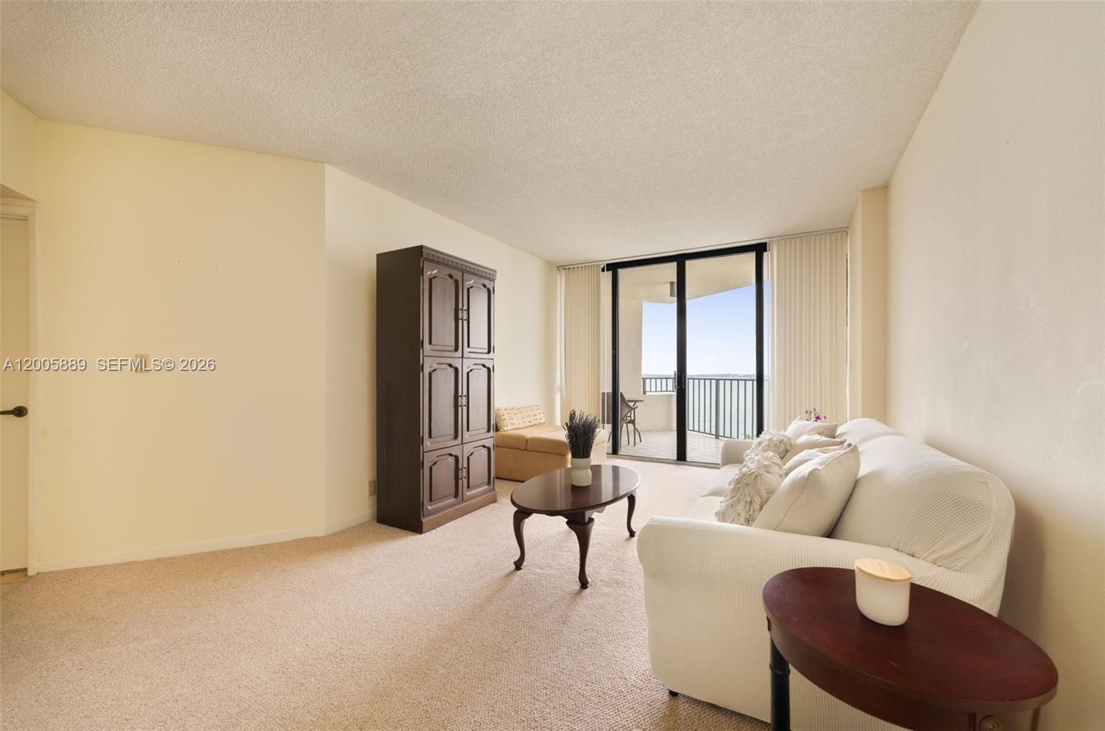 A balcony with wicker furniture overlooks a swimming pool and a large body of water — 520 Brickell Key Dr # A1001, Miami FL 33131, MIAMI, FL