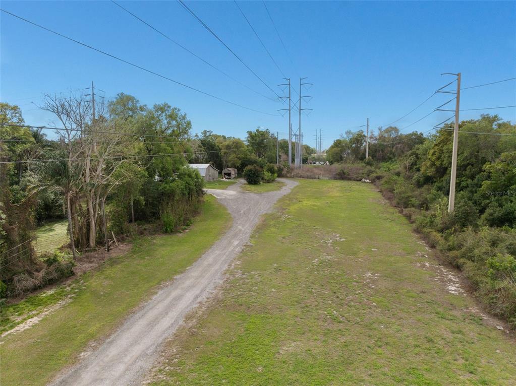An aerial view shows a dirt driveway leading to a small shed on a grassy lot — 6890 COUNTY ROAD 95, PALM HARBOR, FL