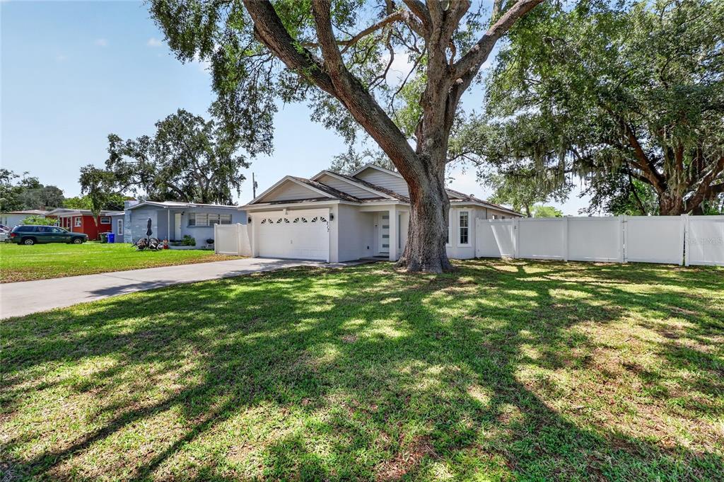 A single-story house with a white garage and a large tree in the front yard — 217 E EDWARD STREET, LAKELAND, FL