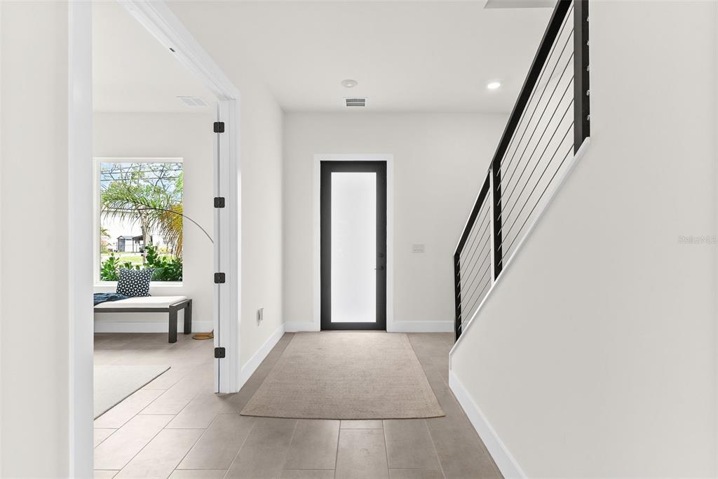 A bright entryway features light tile floors, a modern staircase, and a glass-paneled front door — 4604 W EUCLID AVENUE, TAMPA, FL