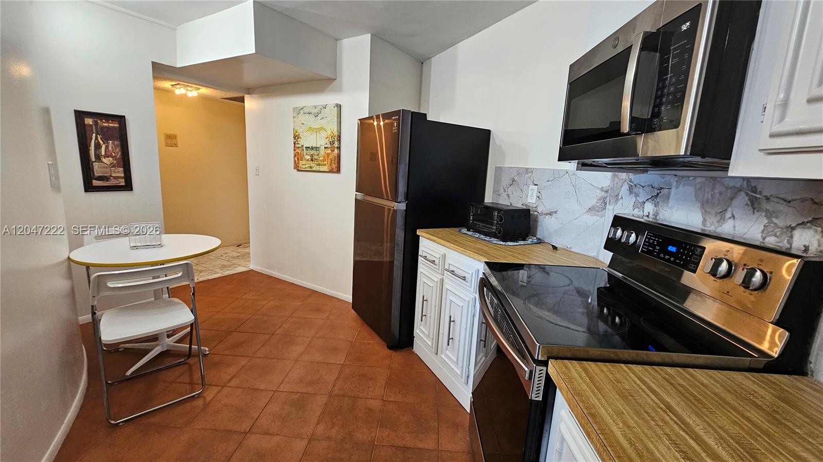 A kitchen features white cabinets, a black refrigerator, a stainless steel stove, and a small table — 800 Parkview Dr # 912, Hallandale Beach FL 33009, HALLANDALE BEACH, FL