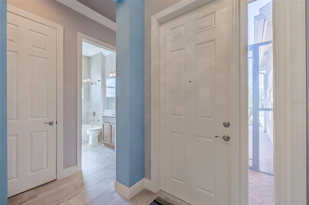 A view of an entryway featuring a white door, a tiled hallway, and a bathroom — 4822 GRAND BANKS DRIVE, WIMAUMA, FL