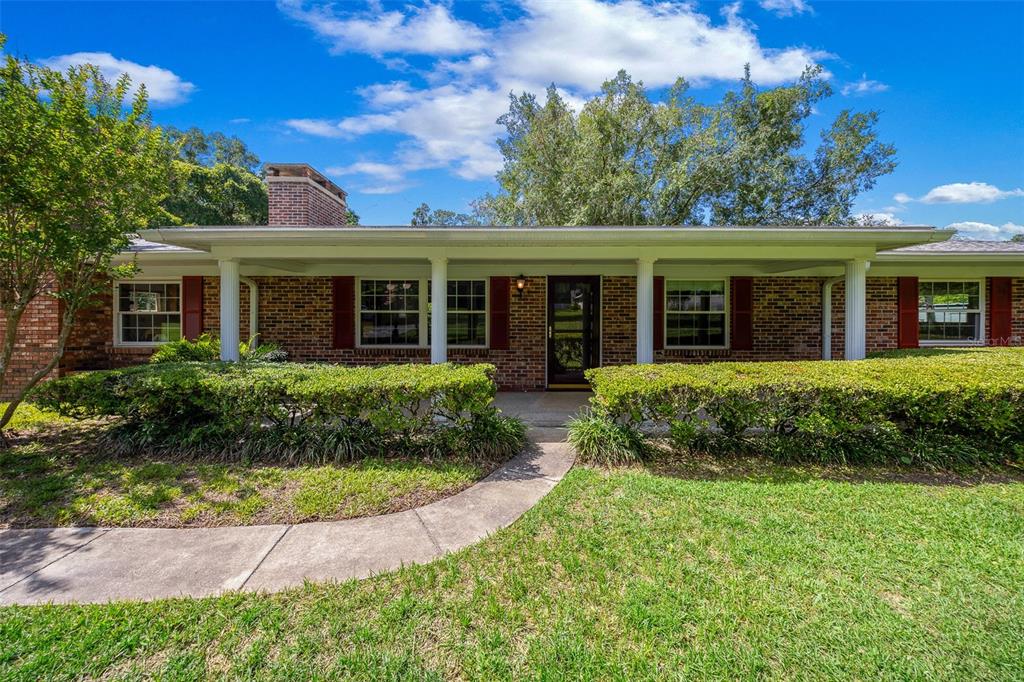 A single-story brick house features a covered front porch, white columns, and green landscaping — 130 SW 69TH STREET, OCALA, FL