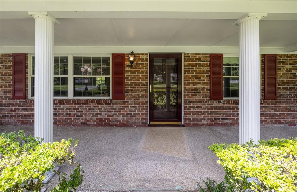 A brick house exterior features a covered porch with white columns and red shutters — 130 SW 69TH STREET, OCALA, FL