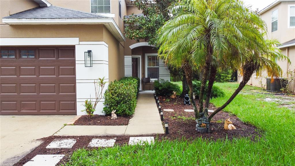 A two-story house exterior with a brown garage door, a palm tree, and a walkway — 15647 GREYROCK DRIVE, SPRING HILL, FL