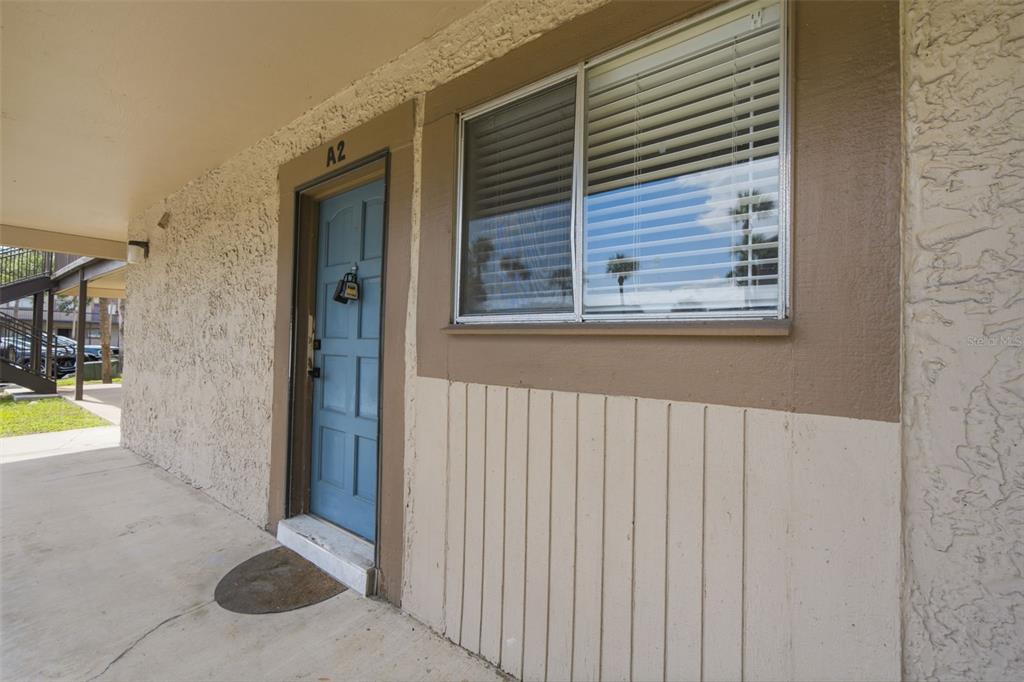 The exterior of a ground-level apartment unit features a blue door labeled A2 — 6314 NEWTOWN CIRCLE UNIT 14A2, TAMPA, FL