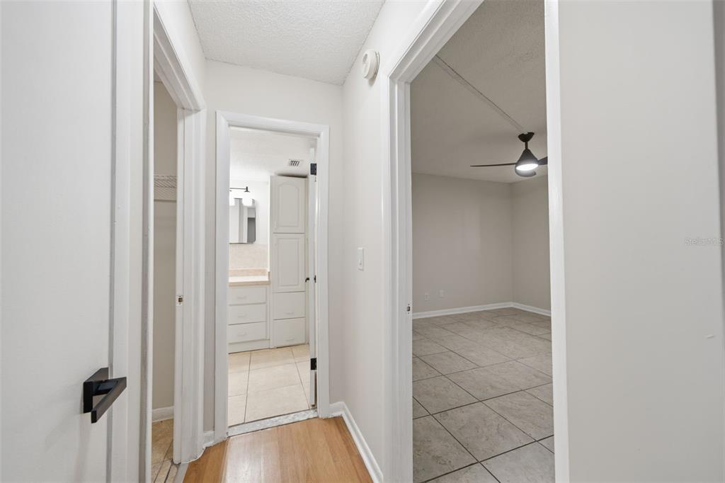 A hallway with wood flooring leads to a tiled bathroom and a tiled bedroom — 6314 NEWTOWN CIRCLE UNIT 14A2, TAMPA, FL