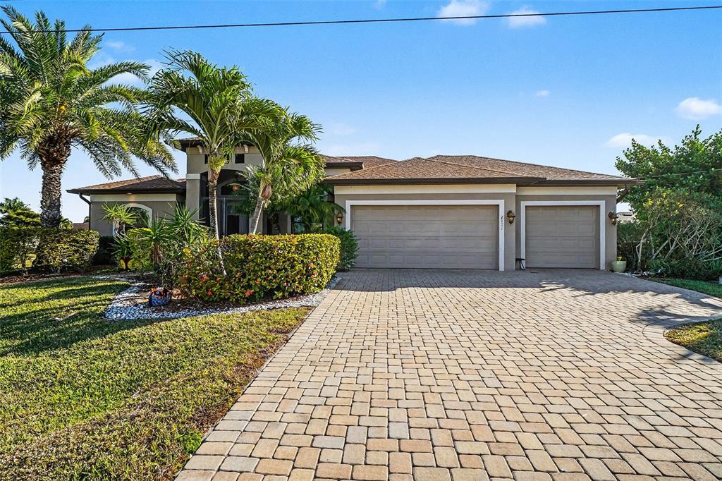 A single-story house with a paved driveway, two garage doors, and palm trees in front — 2127 SE 17TH PLACE, CAPE CORAL, FL