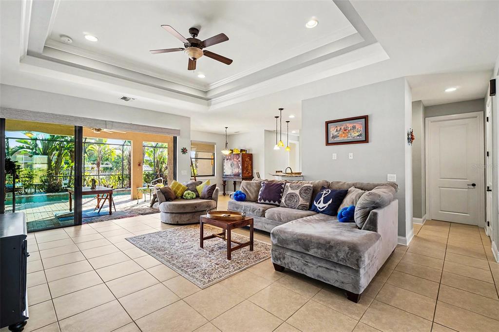 A living room with tile floors, a tray ceiling, and a sliding door to a pool — 2127 SE 17TH PLACE, CAPE CORAL, FL