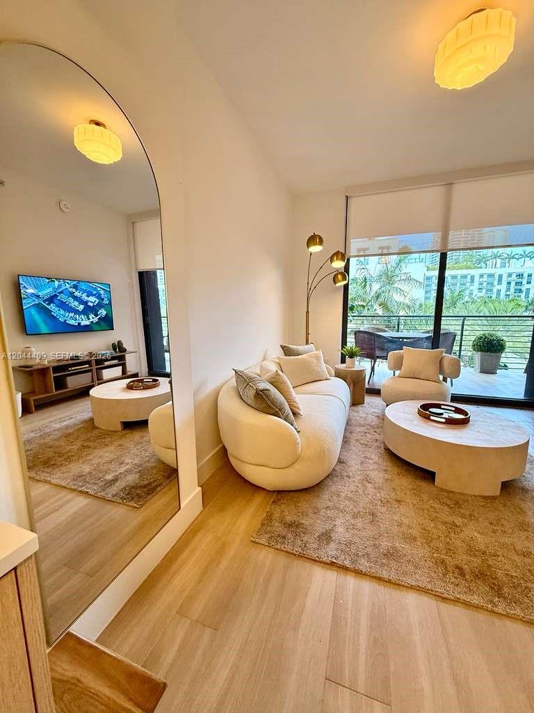 A modern living room features a curved sofa, round coffee table, and a large mirror — 90 NE 32 # 302, Miami FL 33137, MIAMI, FL