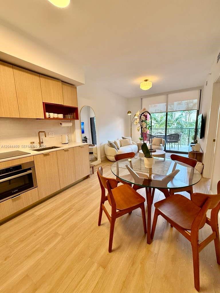 This open-concept kitchen and dining area features light wood cabinetry and a glass-topped table — 90 NE 32 # 302, Miami FL 33137, MIAMI, FL