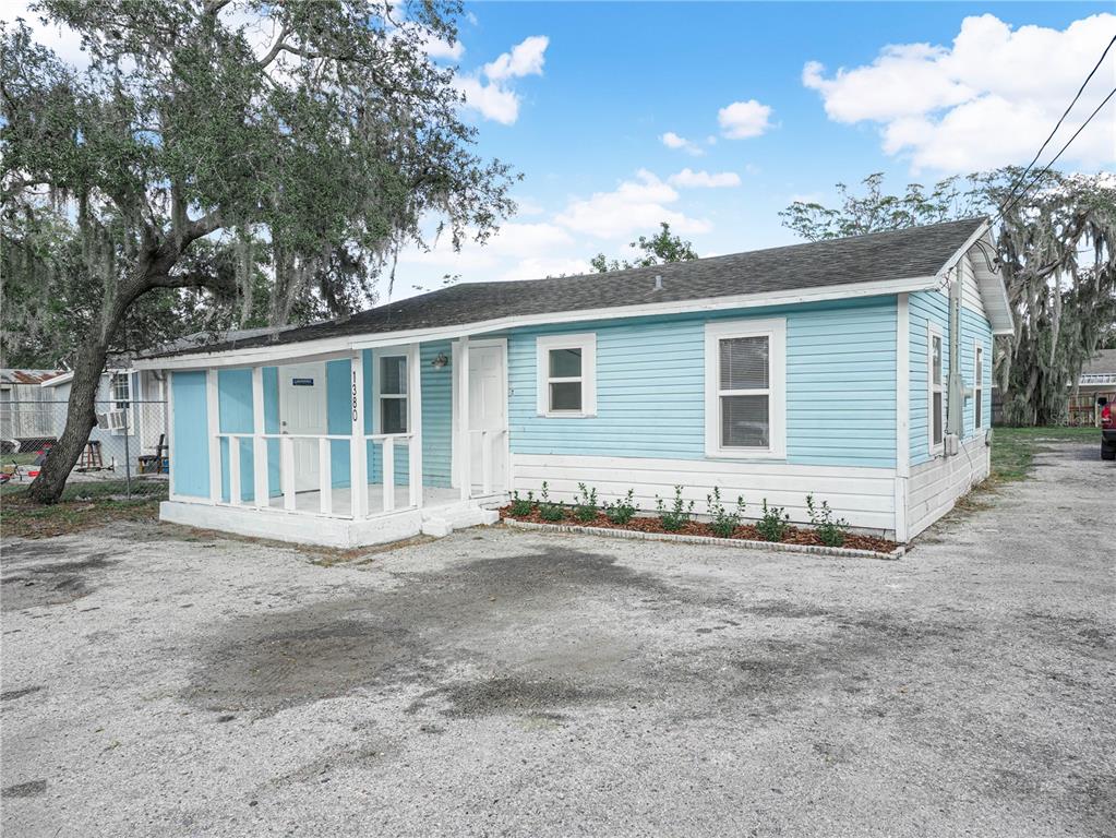 A light blue, single-story house with a white porch and gravel driveway under a sky — 1380 35TH STREET NW, WINTER HAVEN, FL