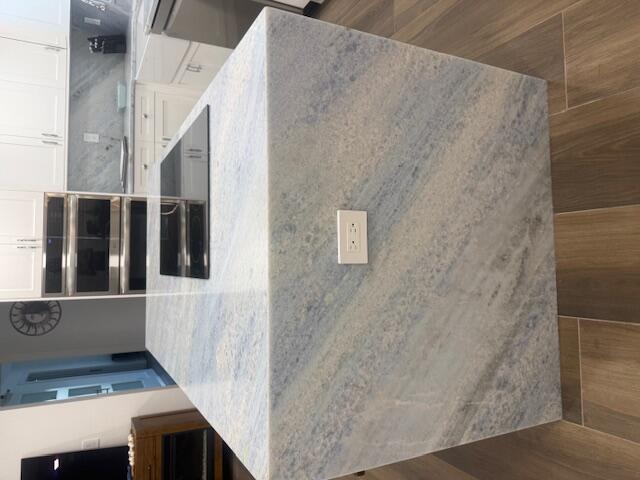 A kitchen island with a blue-toned stone waterfall countertop and a built-in glass cooktop — 5520 N Ocean Boulevard # 111, Ocean Ridge FL 33435, OCEAN RIDGE, FL