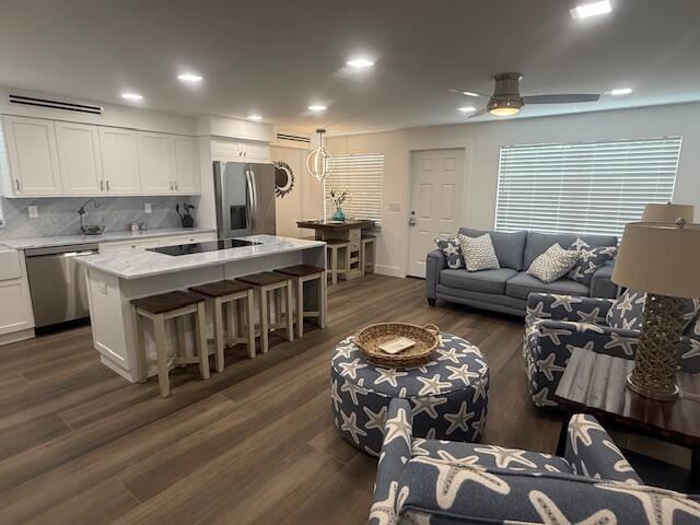 An open-concept kitchen and living area features white cabinetry, a marble island, and coastal decor — 5520 N Ocean Boulevard # 111, Ocean Ridge FL 33435, OCEAN RIDGE, FL