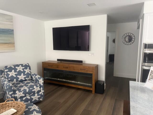 A living room features a wall-mounted television above a wooden fireplace console and patterned armchair — 5520 N Ocean Boulevard # 111, Ocean Ridge FL 33435, OCEAN RIDGE, FL