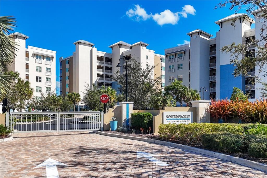 The exterior view shows a gated entrance to a multi-story apartment complex with landscaping — 10510 BOARDWALK LOOP UNIT 602, LAKEWOOD RANCH, FL