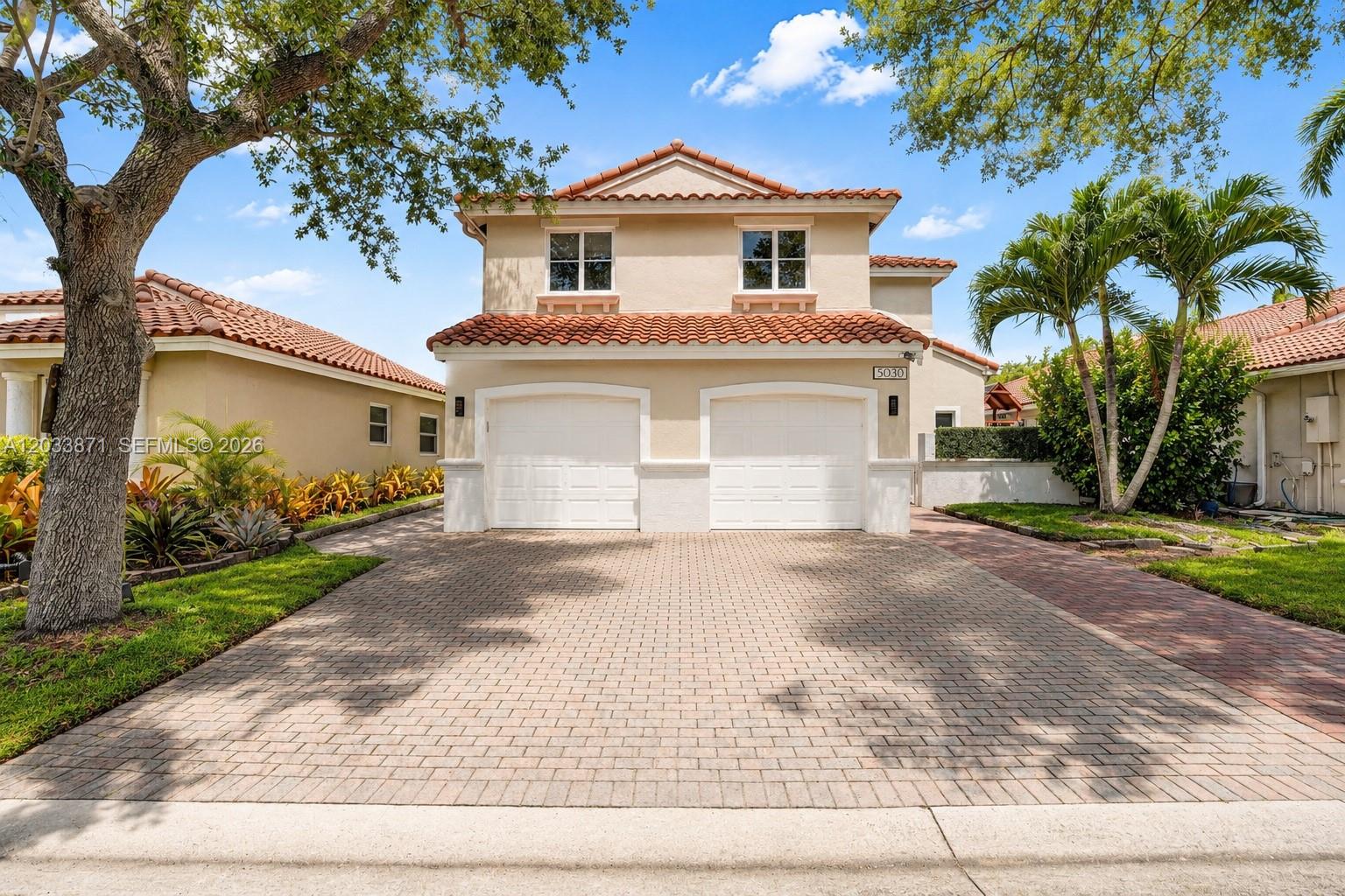 A two-story house with a two-car garage and a paved driveway under a blue sky — 5080 SW 34th Ter, Hollywood FL 33312, HOLLYWOOD, FL