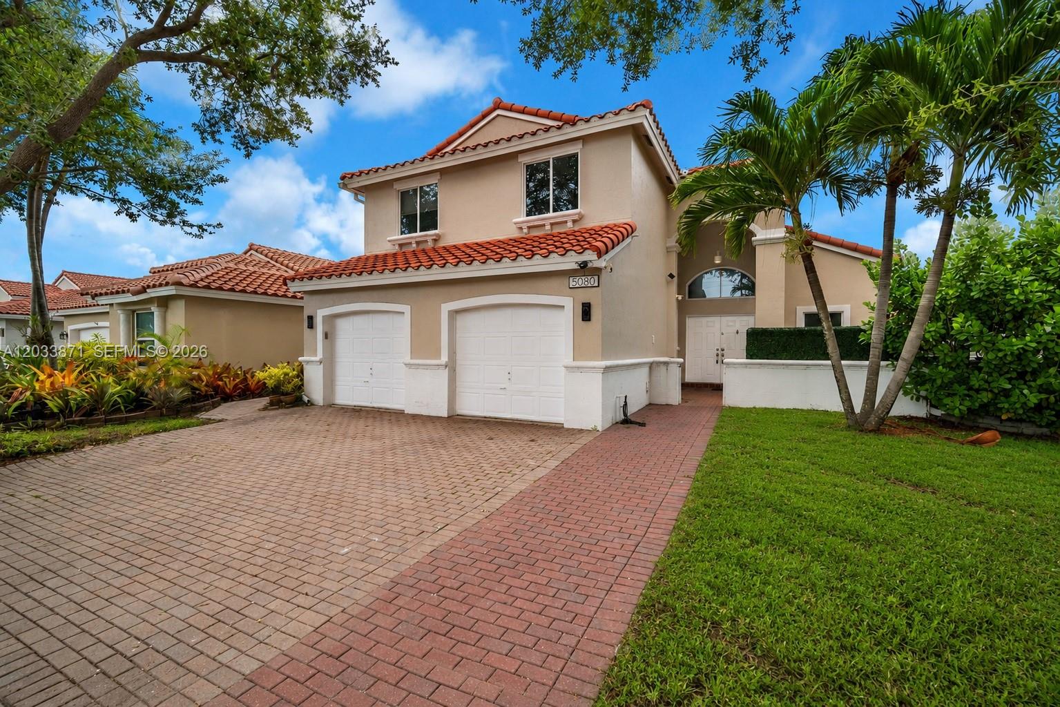 A two-story house with a red tile roof, two garage doors, and a brick driveway — 5080 SW 34th Ter, Hollywood FL 33312, HOLLYWOOD, FL