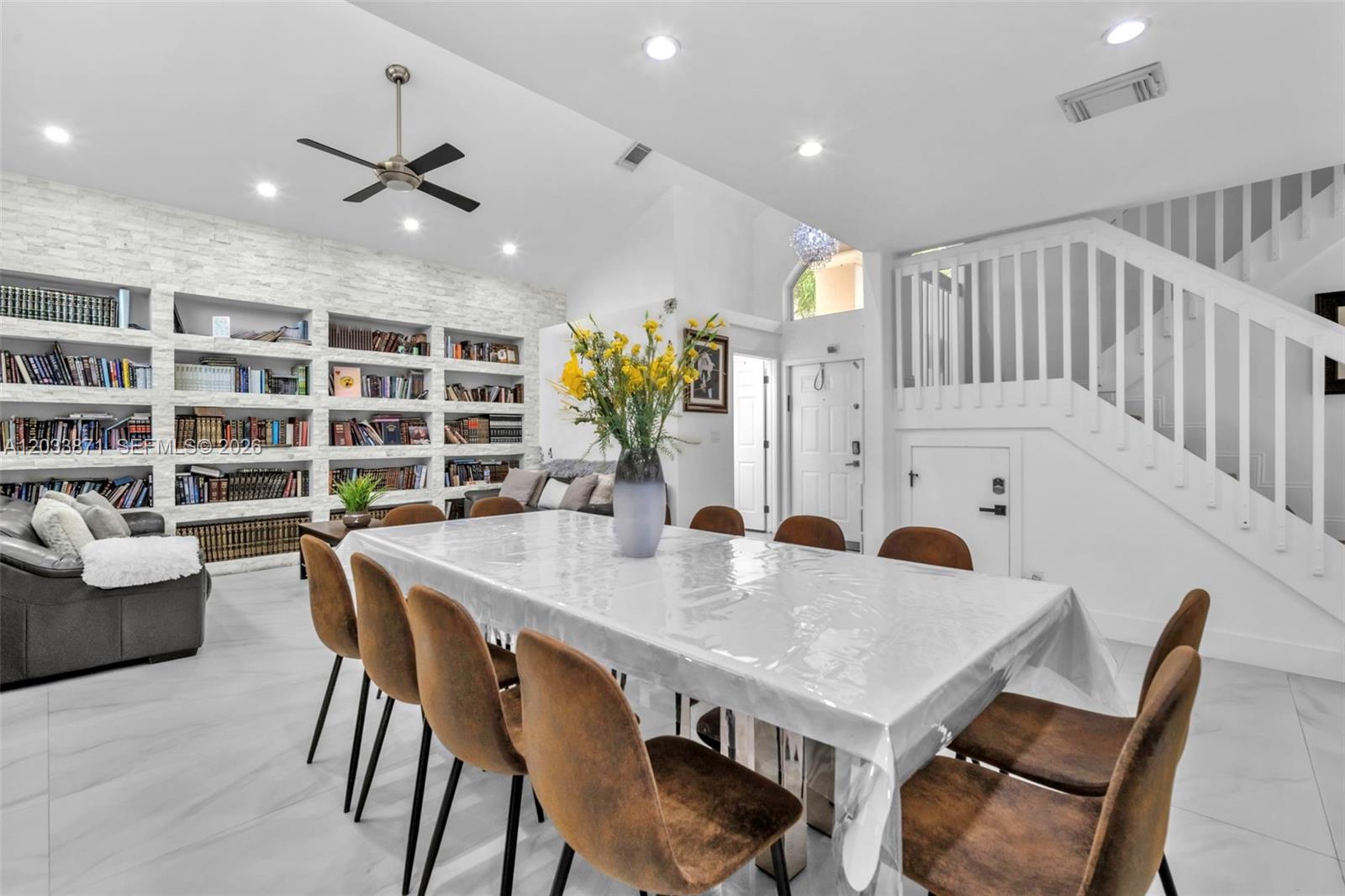 A dining room features a large table with brown chairs, built-in bookshelves, and stairs — 5080 SW 34th Ter, Hollywood FL 33312, HOLLYWOOD, FL