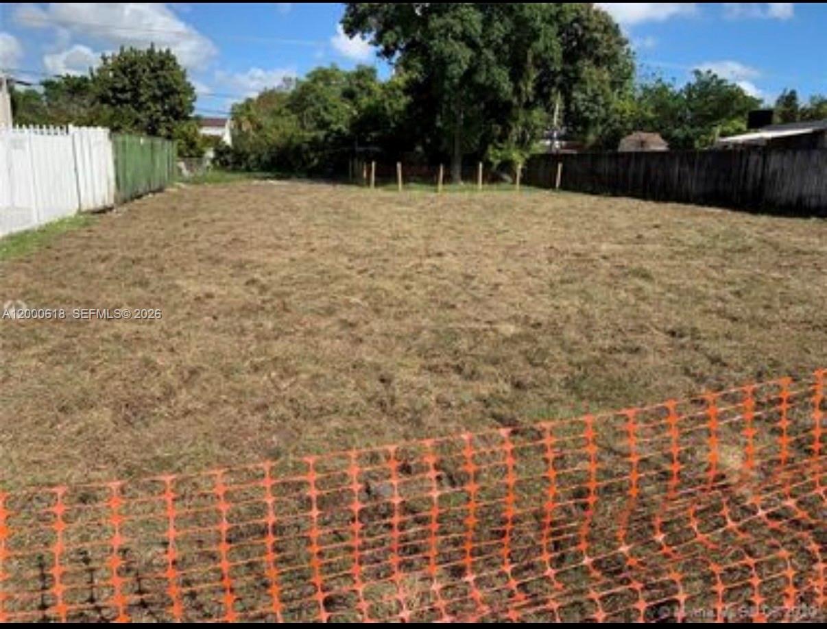 A vacant, grassy residential lot is enclosed by a white fence and a wooden fence — 601 sw 44th ct, Miami FL 33134, MIAMI, FL