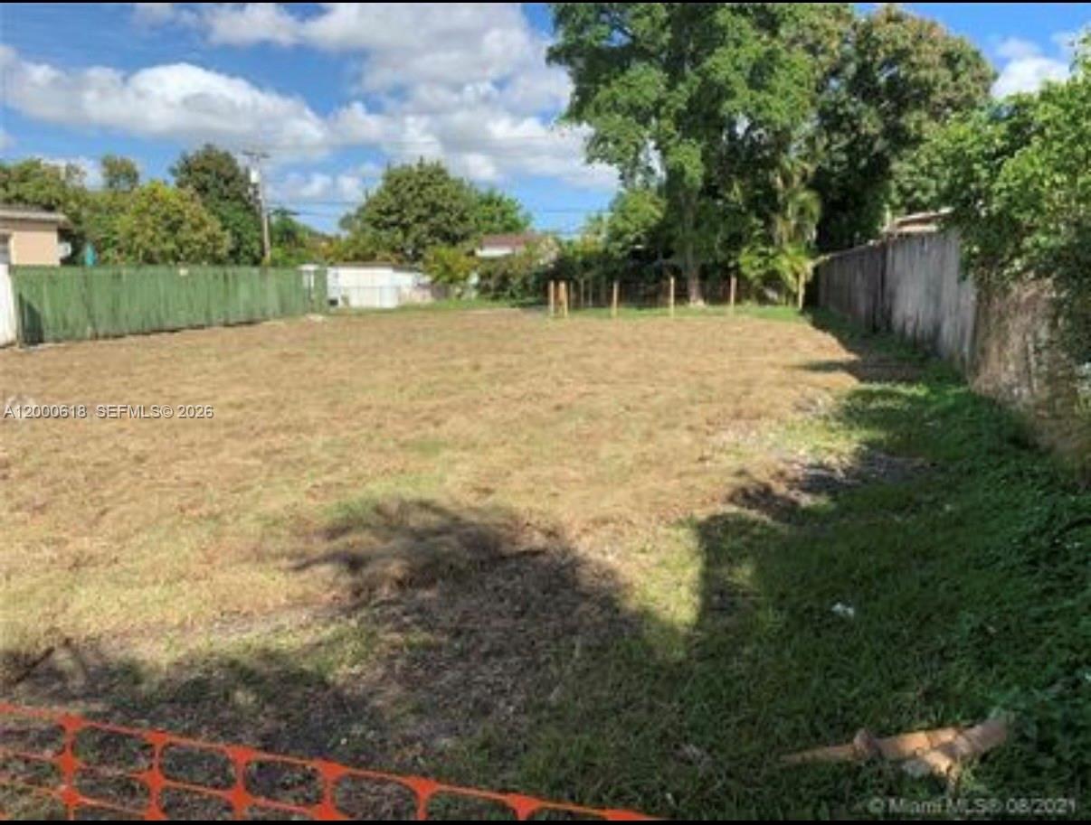 A vacant, grassy residential lot is enclosed by a green fence and a concrete wall — 601 sw 44th ct, Miami FL 33134, MIAMI, FL