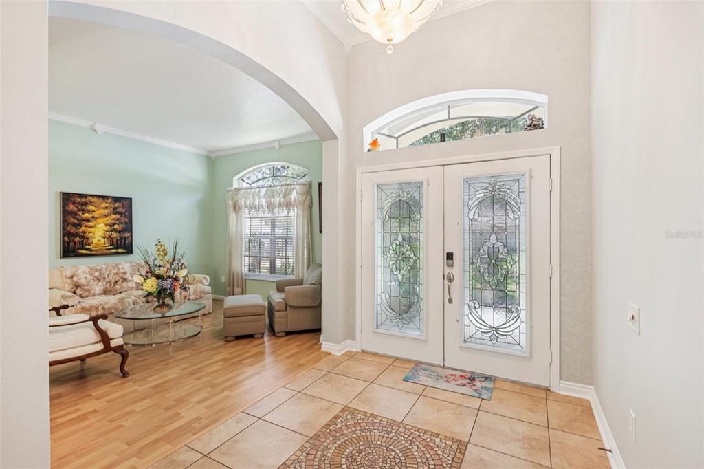 A tiled entryway leads into a living room with light wood flooring and arched openings — 1901 HEARTLAND CIRCLE, VALRICO, FL