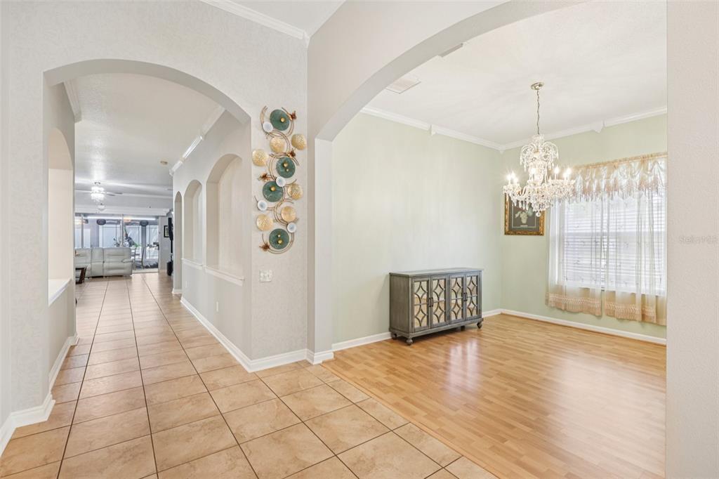 A tiled hallway leads to a dining room with wood flooring and a crystal chandelier — 1901 HEARTLAND CIRCLE, VALRICO, FL