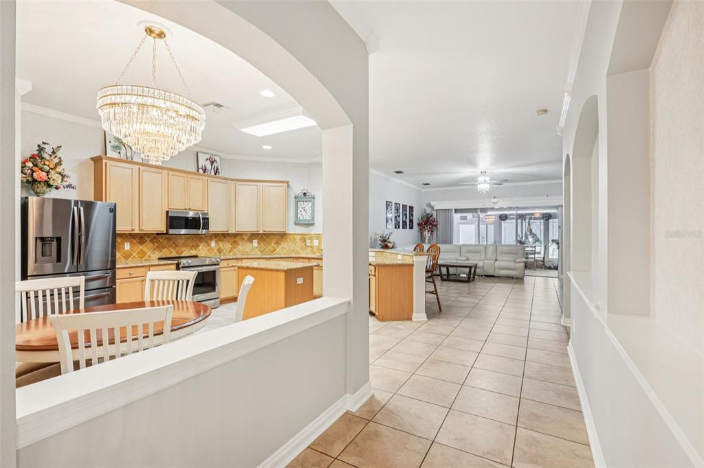 A view through an arched opening into a kitchen with light wood cabinets and tile flooring — 1901 HEARTLAND CIRCLE, VALRICO, FL