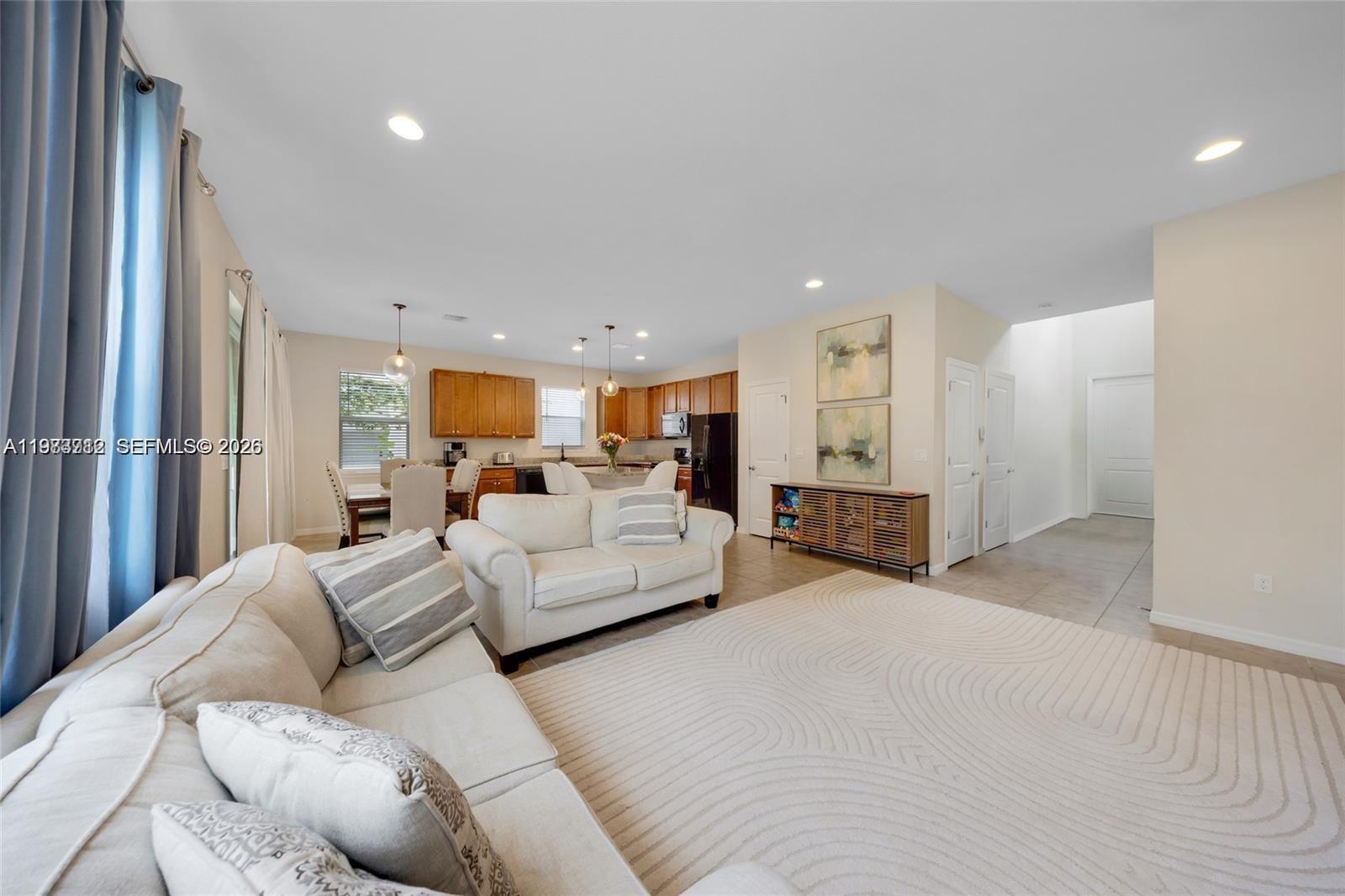 A living room with light-colored sofas and a rug opens to a kitchen with cabinets — 932 Banyan Dr, Hollywood FL 33021, HOLLYWOOD, FL