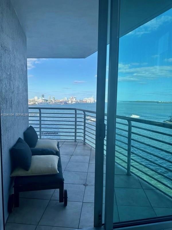 A balcony with a lounge chair overlooks a bay and a distant city skyline — 325 S Biscayne Blvd # 1523, Miami FL 33131, MIAMI, FL