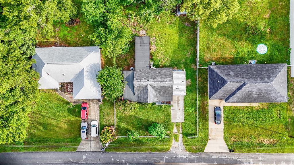An aerial view shows three houses with driveways and lawns along a paved road — 4010 SE 138TH PLACE, SUMMERFIELD, FL