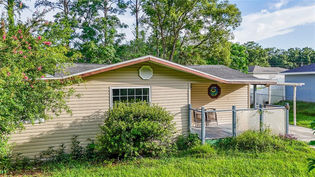 A tan, single-story house with horizontal siding features a front porch and a large window — 4010 SE 138TH PLACE, SUMMERFIELD, FL