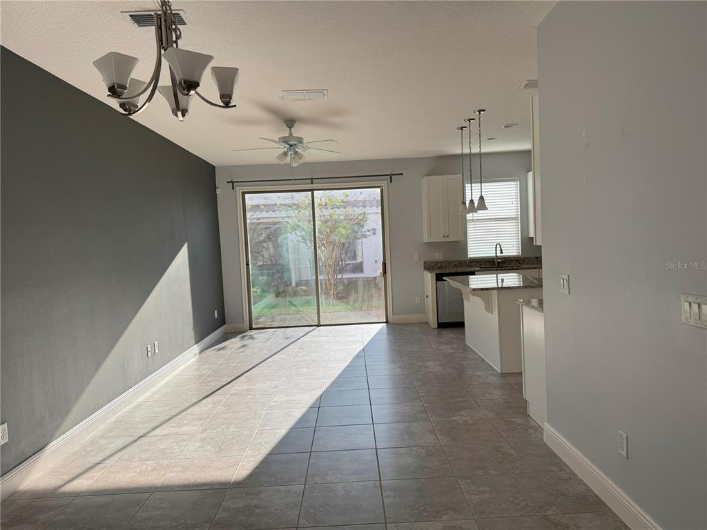A dining area with tile floors, a dark accent wall, and a sliding glass door — 13963 ARCLID STREET, ORLANDO, FL