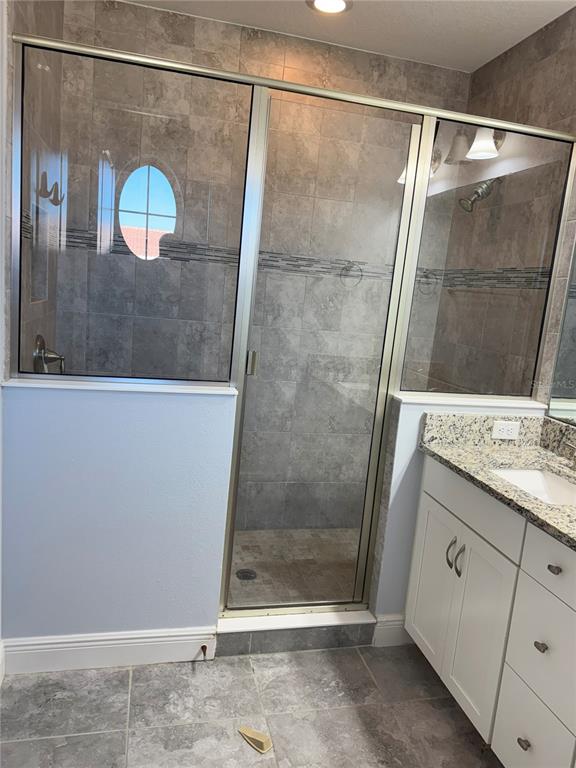 A bathroom features a tiled walk-in shower with a glass door next to a vanity — 13963 ARCLID STREET, ORLANDO, FL