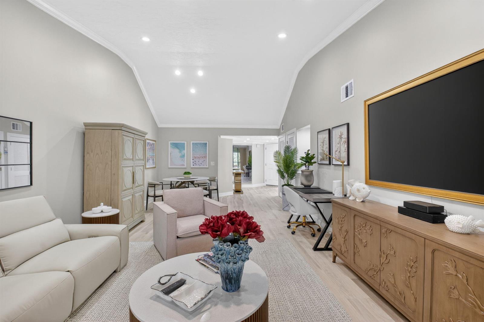 A living room features a vaulted ceiling, light wood flooring, a television, and neutral furniture — 7455 Glendevon Lane # 206, Delray Beach FL 33446, DELRAY BEACH, FL