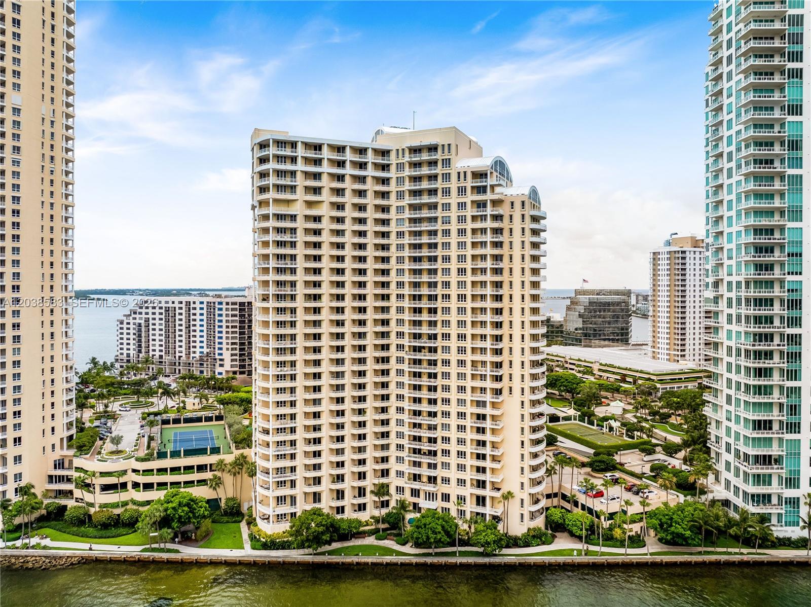 An exterior view of a tall, beige residential high-rise building situated along a waterfront — 888 Brickell Key Dr # 1010, Miami FL 33131, MIAMI, FL