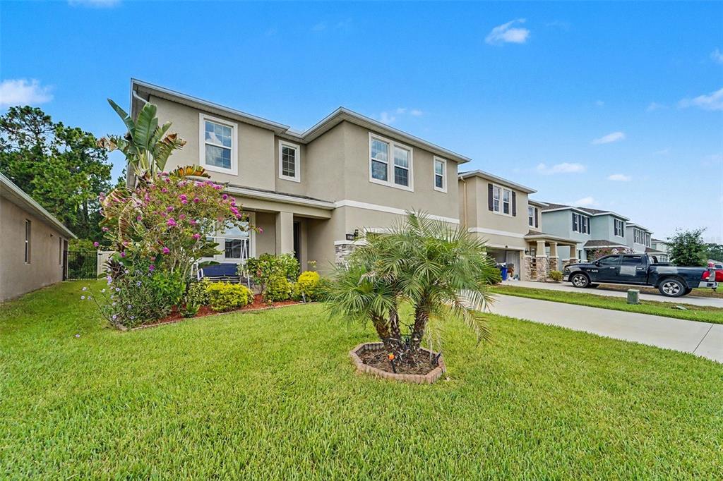 A two-story suburban house with a tan exterior, a front lawn, and a parked truck — 3221 LIVING CORAL DRIVE, ODESSA, FL