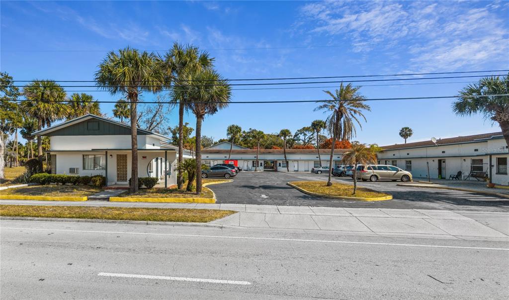 A single-story motel building with a parking lot and palm trees under a blue sky — 619 N RIDGEWOOD AVENUE, DAYTONA BEACH, FL