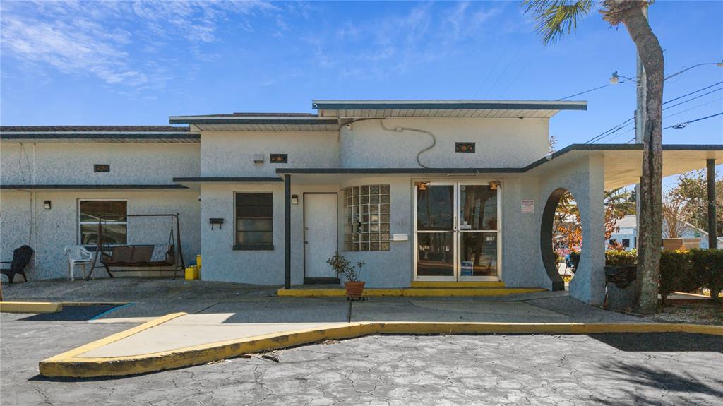 The exterior of a single-story building features a glass-paneled entrance, a carport, and stucco walls — 619 N RIDGEWOOD AVENUE, DAYTONA BEACH, FL