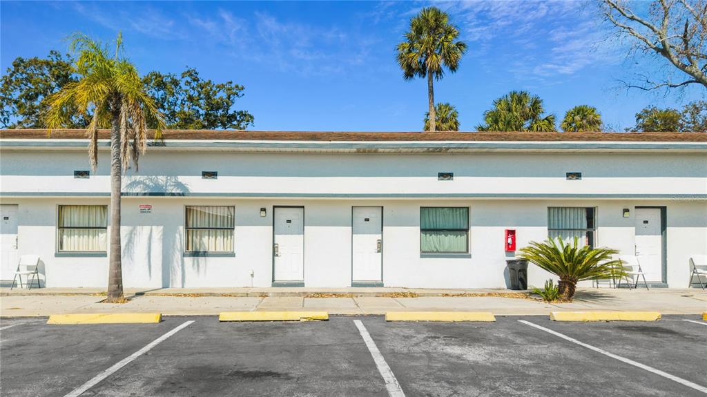 A single-story motel building with white stucco walls, multiple doors, and a parking lot — 619 N RIDGEWOOD AVENUE, DAYTONA BEACH, FL