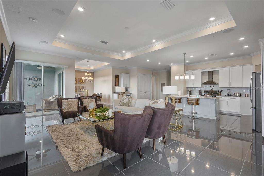 An open-concept living room and kitchen feature glossy tile floors and a tray ceiling — 4751 CLOCK TOWER DRIVE UNIT 402, KISSIMMEE, FL