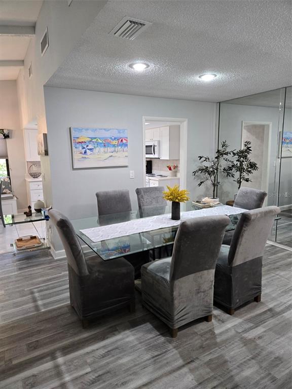 A dining room features a glass table, gray upholstered chairs, and a beach-themed wall painting — 3235 BUCKHORN DRIVE, CLEARWATER, FL