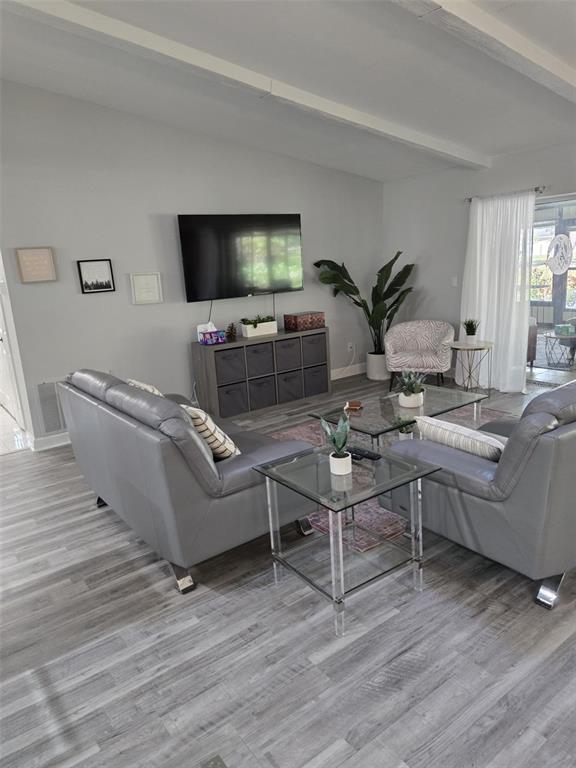 A living room features gray flooring, two gray sofas, a glass coffee table, and a television — 3235 BUCKHORN DRIVE, CLEARWATER, FL