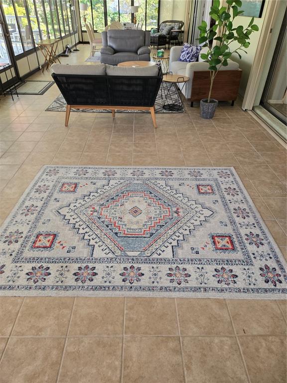 A sunroom features tile flooring, a patterned area rug, and various pieces of living room furniture — 3235 BUCKHORN DRIVE, CLEARWATER, FL