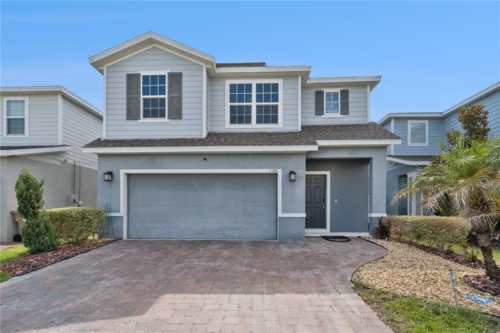 A two-story house with a gray stucco exterior, a two-car garage, and a paver driveway — 4406 SILVER CREEK STREET, KISSIMMEE, FL