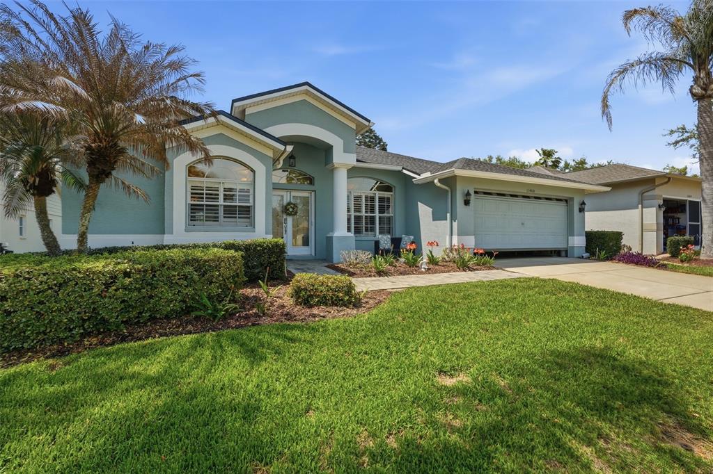 A light blue single-story house features a two-car garage, arched entryway, and landscaped front yard — 11408 ALDEN COURT, HUDSON, FL