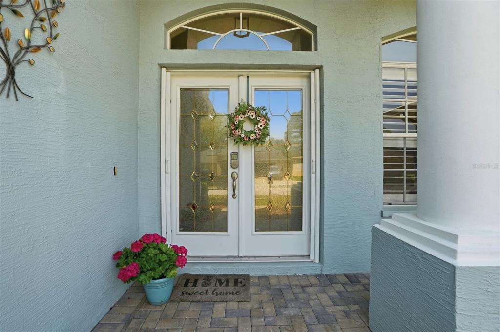 A light blue exterior wall features a double glass door entrance with a floral wreath — 11408 ALDEN COURT, HUDSON, FL