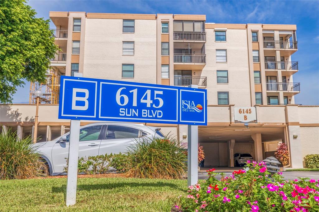A blue sign stands in front of a multi-story apartment building with balconies — 6145 SUN BOULEVARD UNIT 304, ST PETERSBURG, FL