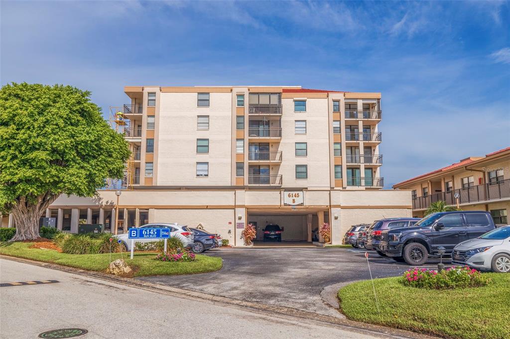A multi-story apartment building with a covered parking entrance and a large tree nearby — 6145 SUN BOULEVARD UNIT 304, ST PETERSBURG, FL